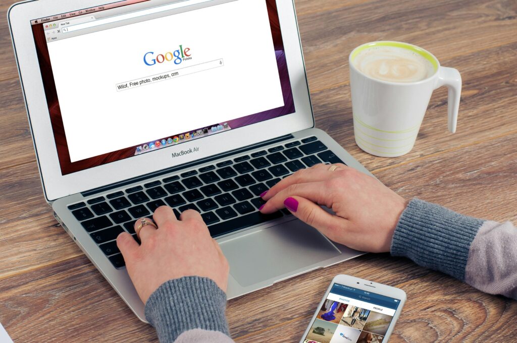 Hands typing on MacBook Air with Google search open, coffee nearby. 10 Digital Marketing Skills to Learn Now .Top 5 Affordable Digital Marketing Agencies