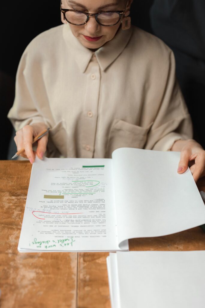 Senior woman reviewing a screenplay script with notes and edits, showcasing expertise.