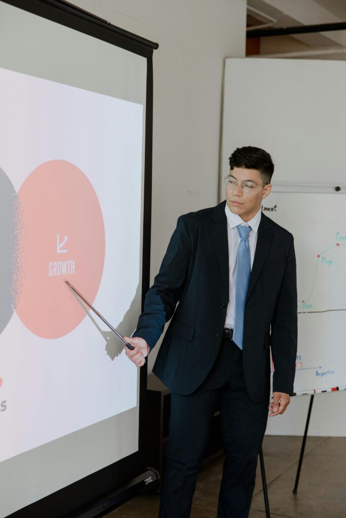 Businessman in a suit presenting a growth strategy using a pointer on a projector screen.