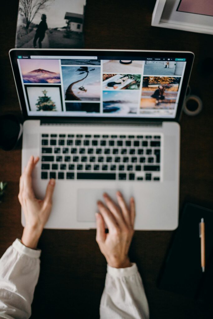 Hands using a laptop to browse photo galleries, illustrating digital creativity and remote work. Top 10 ways to built digital marketing agency